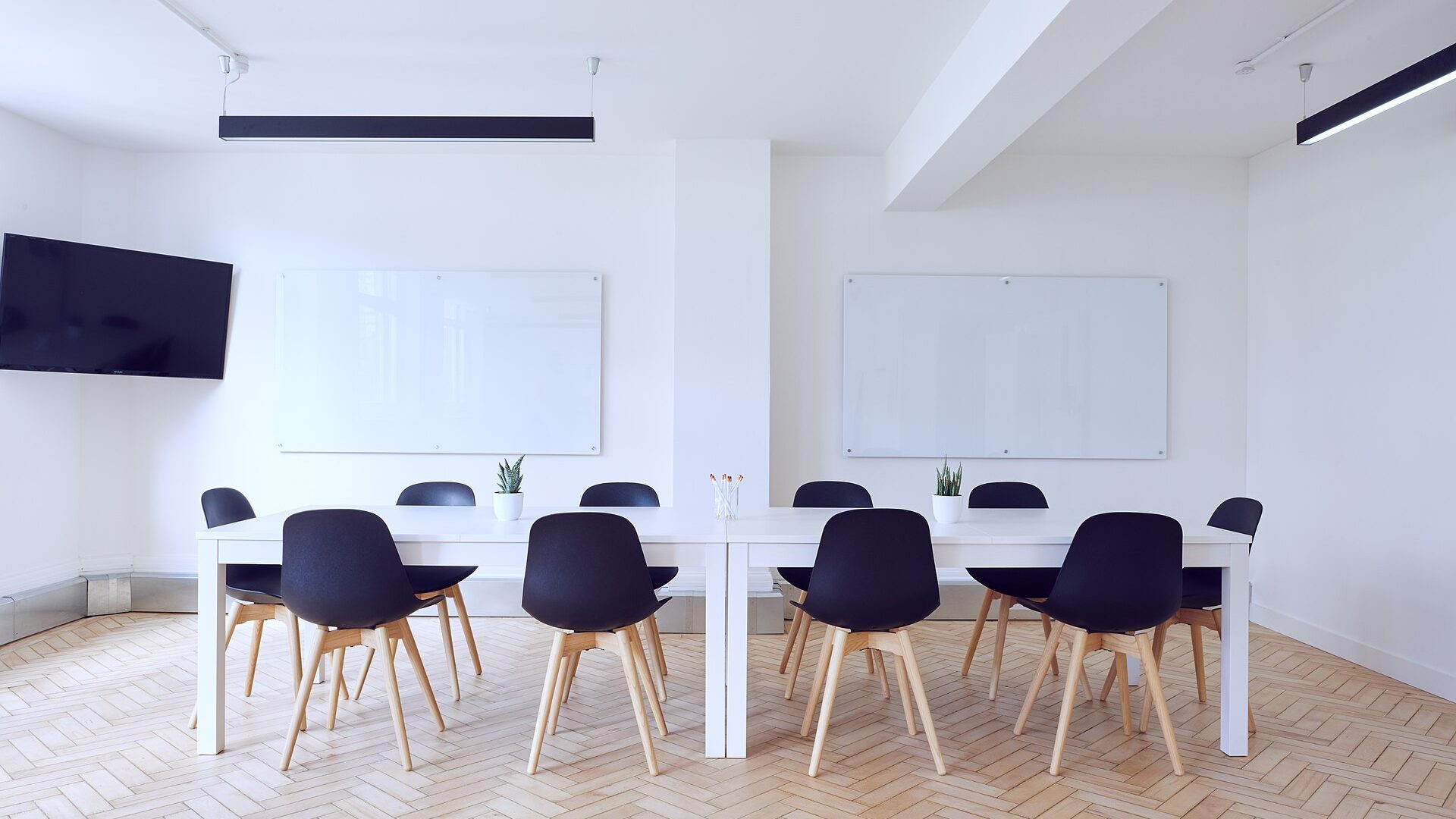 Bright, minimal conference room with a white table and black chairs