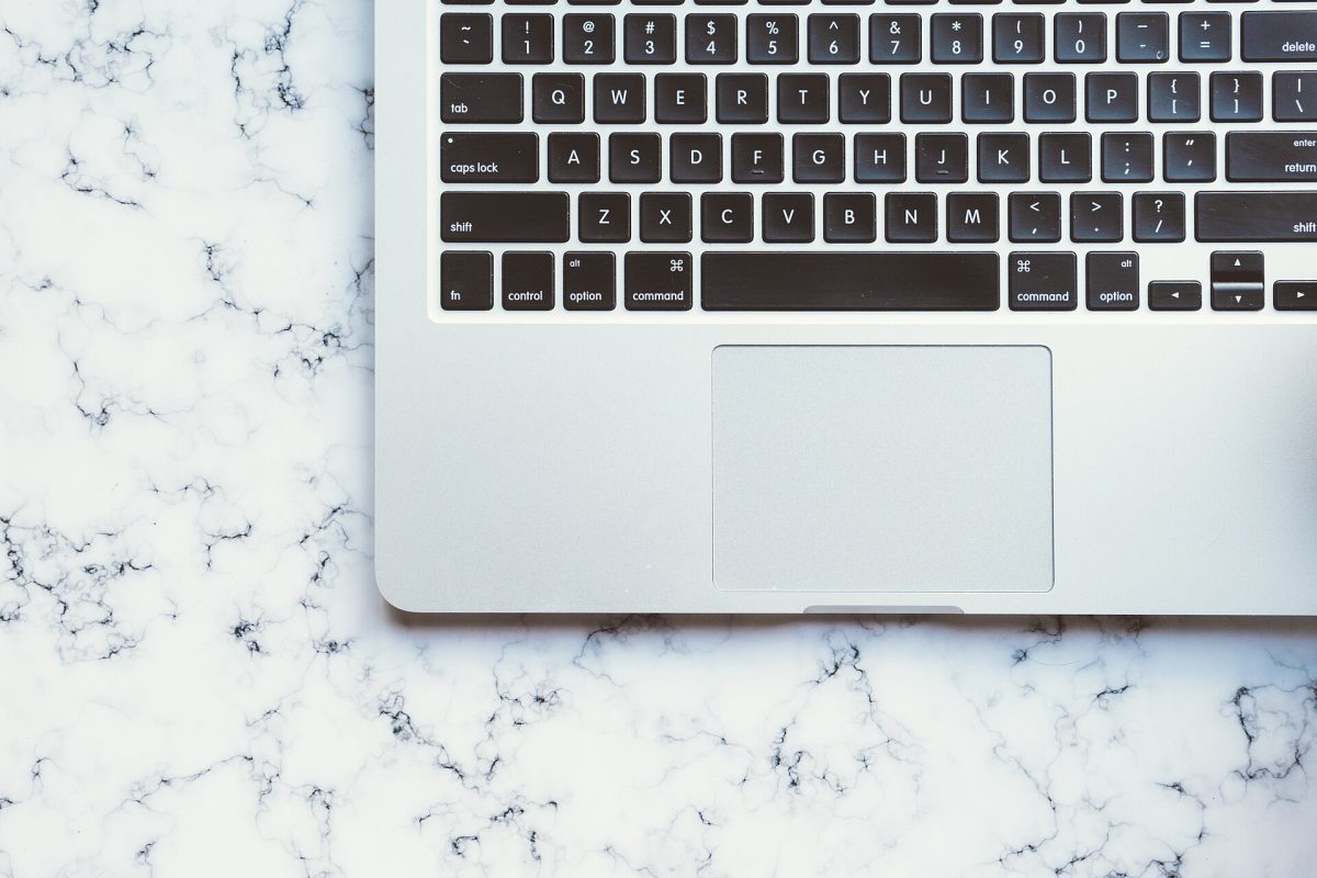 Laptop keyboard and trackpad on a white marble desk